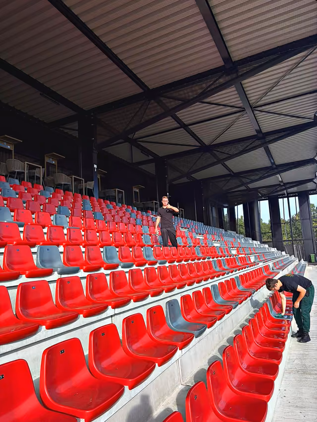 Deelnemers maken de stoeltjes op de tribune schoon