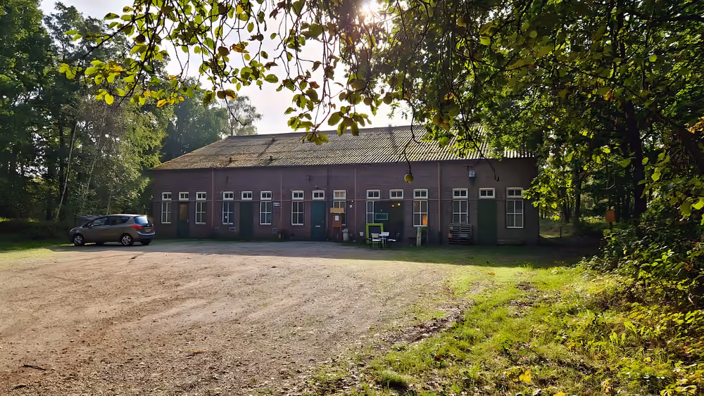 Het langgerekte bakstenen gebouw van Mariapeel in de ochtendzon, tussen de bomen