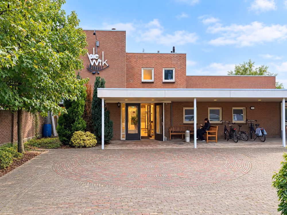 De ingang van De Wik met de overkapping, het plein en de fietsen voor de deur