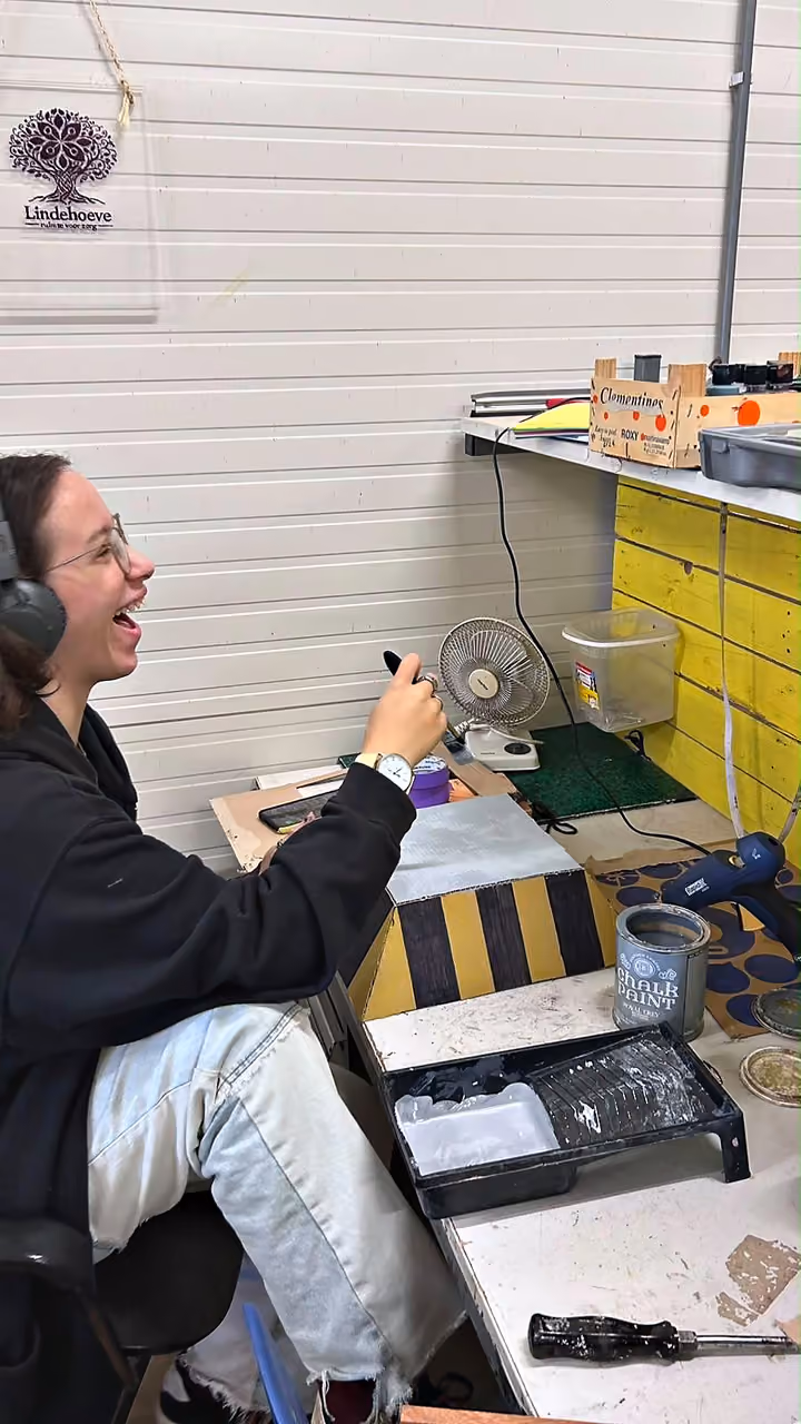 Een deelnemer lacht tijdens het werk in de werkplaats