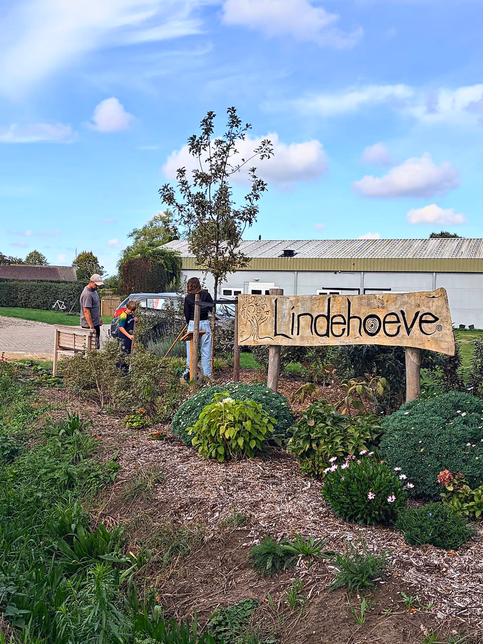 Deelnemers aan het werk in de tuin bij het Lindehoeve-bord