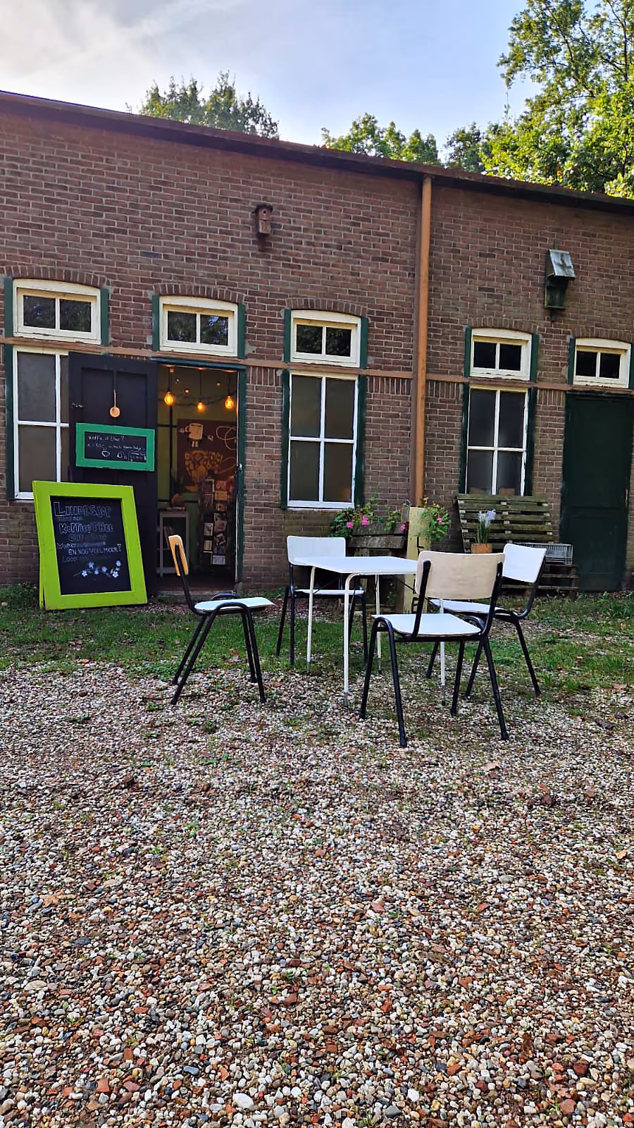 Het terras met stoelen en een krijtbord voor het gebouw