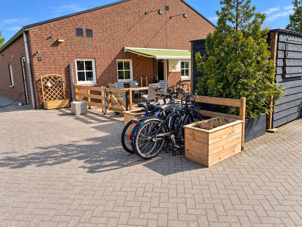 De voorkant van locatie Liessel in de zon, met het terras en de fietsen voor de deur